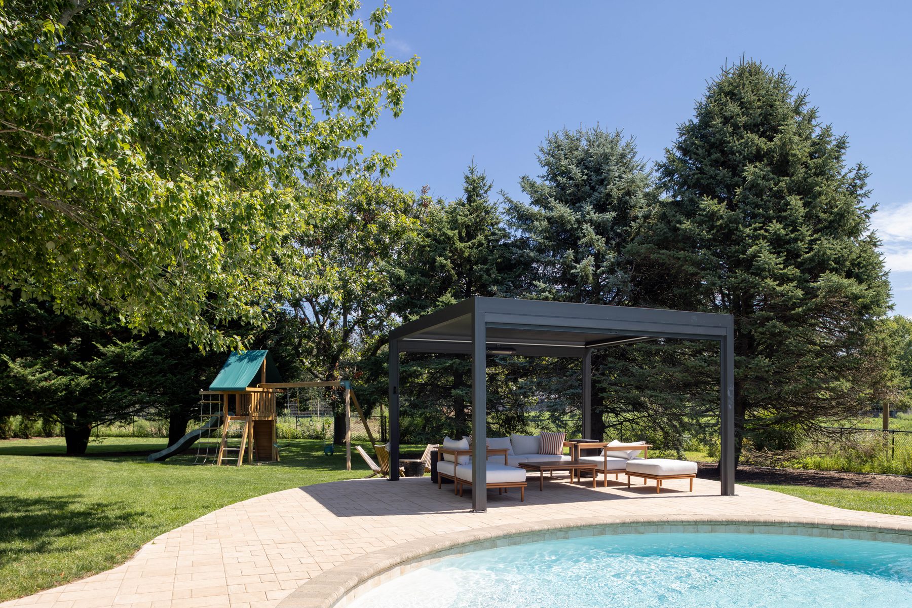 Backyard with heated saltwater pool, pergola, and play set on the lawn